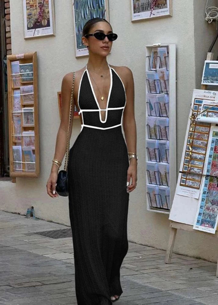 Woman in a black and white dress standing on a street with posters and newspapers in the background.