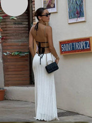 Woman in a white dress with black accents standing in front of a 'Saint-Tropez' sign.