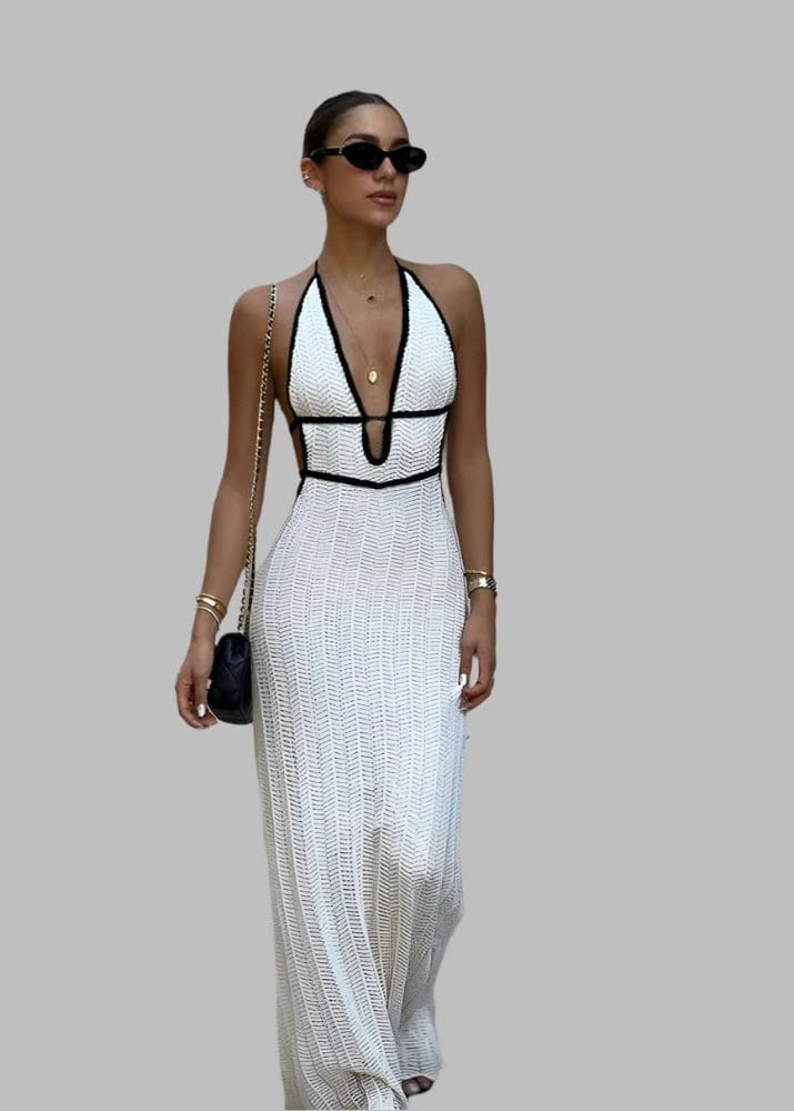 Woman in a white and black dress standing in front of a wall with posters and brochures.