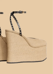 Beige wedge sandals with black straps on a beige background