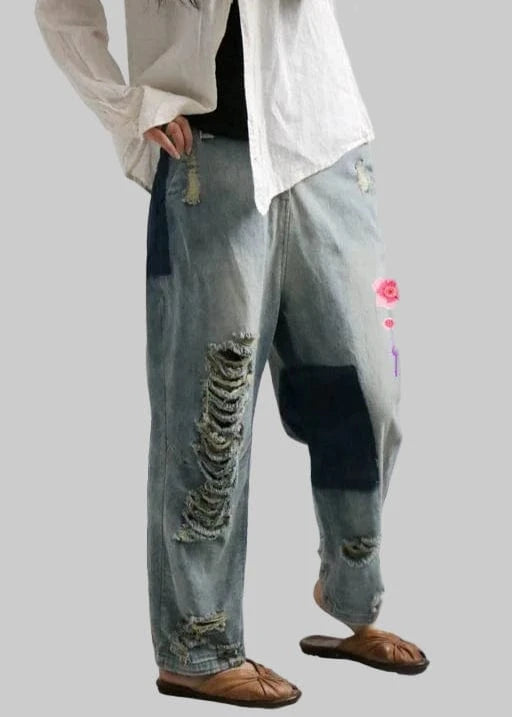 Person wearing ripped jeans with a white shirt and sandals on a light gray background