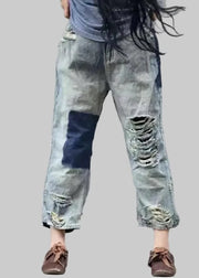 Person wearing distressed denim pants with a blurred background