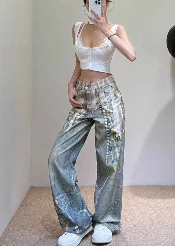 Person wearing a white crop top and patterned jeans taking a mirror selfie.