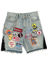 Denim shorts with various colorful patches on a white background