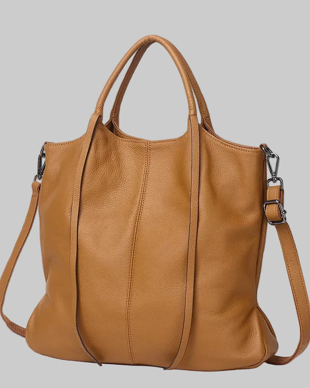 A tan cowhide leather shoulder bag with dual top handles and a detachable shoulder strap, shown against a light blue background with promotional text overlay.