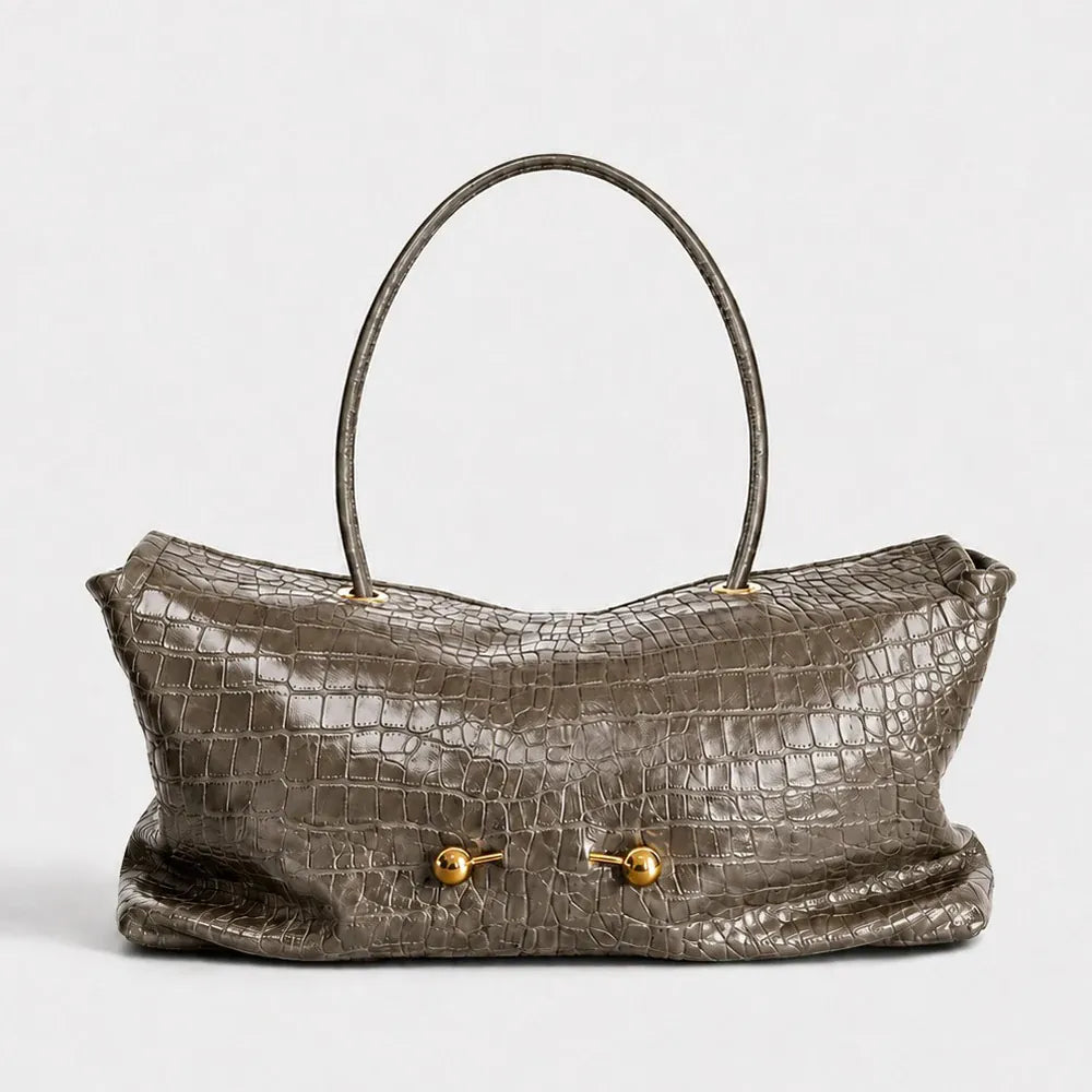 A metallic taupe crocodile-embossed leather handbag with a single top handle and gold-tone hardware, shown against a plain light gray background.
