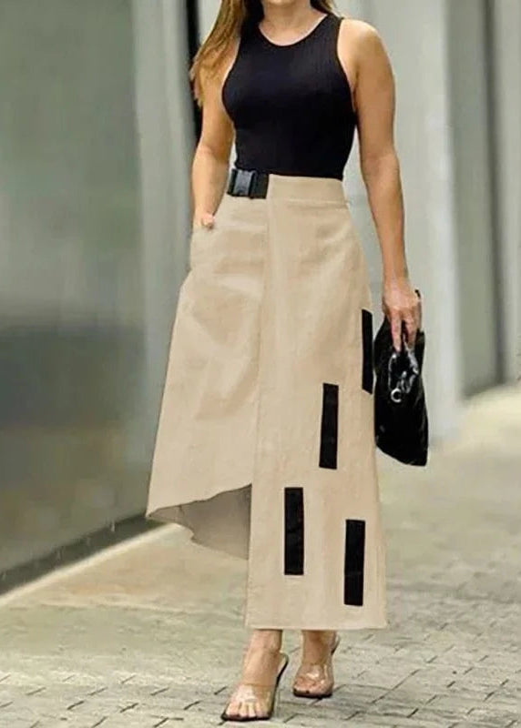 Woman wearing a black sleeveless top and beige skirt with black accents on a street.