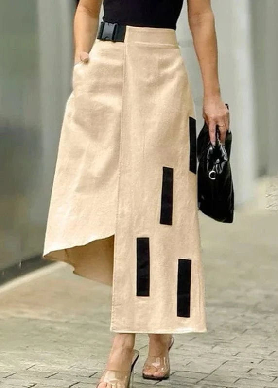 Woman wearing a beige skirt with black accents and holding a black clutch.