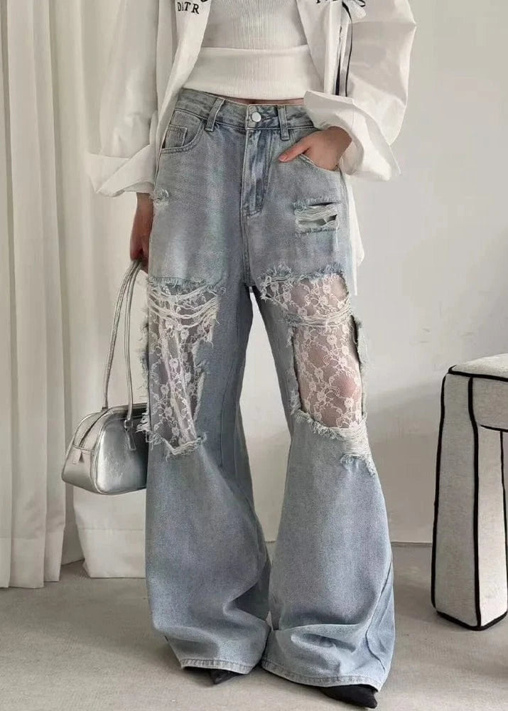 Person wearing light blue jeans with lace patches in a minimal indoor setting