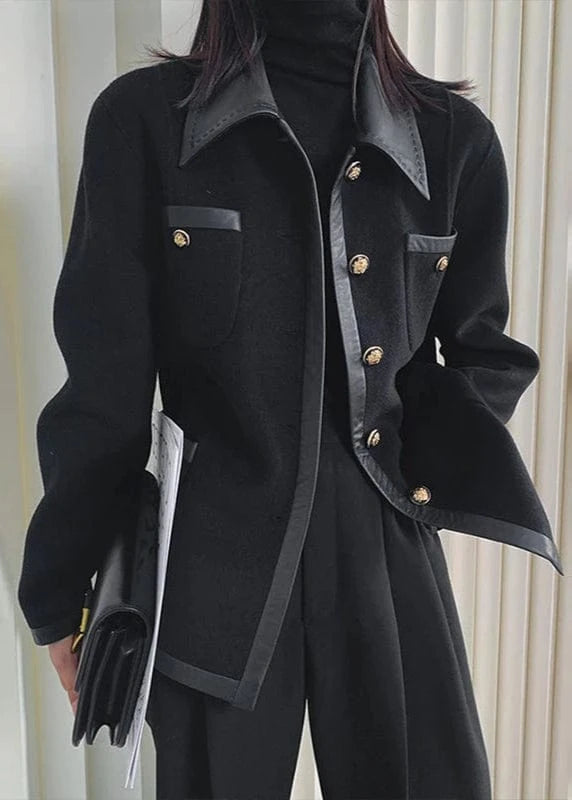Person wearing a black coat with gold buttons against a neutral background