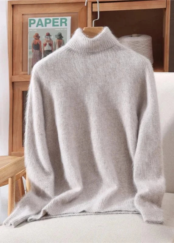 Light gray turtleneck sweater on a chair with a wooden shelf and magazine in the background