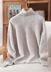 Light gray turtleneck sweater on a chair with a wooden shelf and magazine in the background