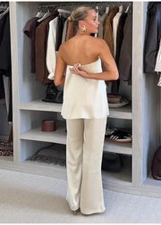 Woman in a white outfit standing in front of an open closet with clothes hanging on racks.