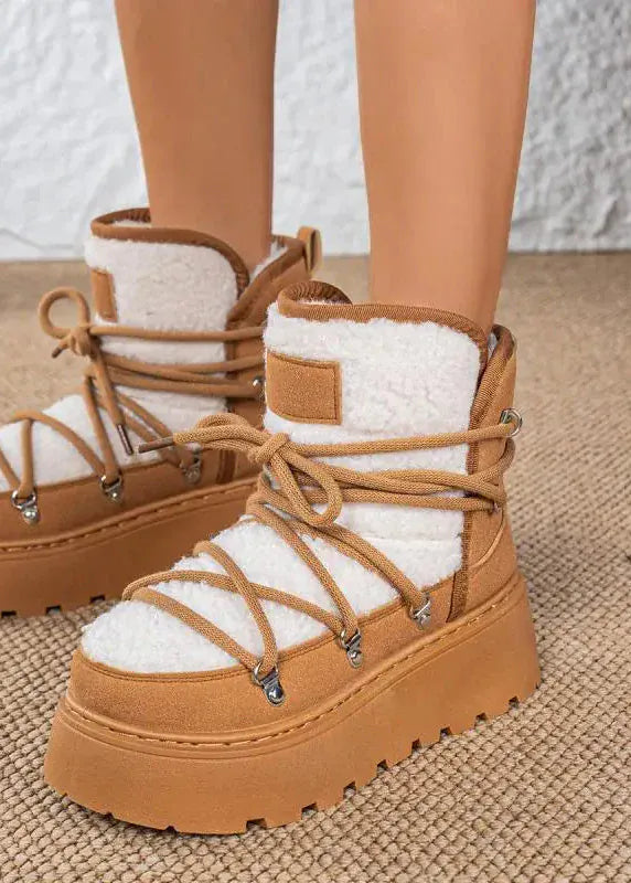 Brown platform boots with white fur lining worn by a person on a textured surface.