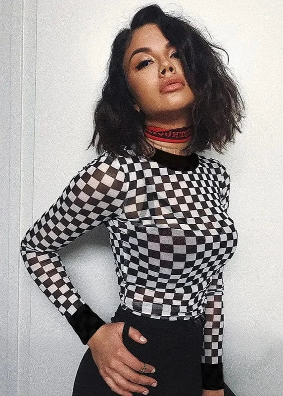 Person wearing a black and white checkered long-sleeve top against a plain background