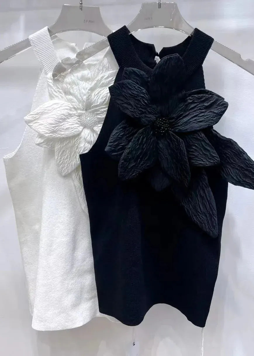 White and black sleeveless dresses with floral details on hangers against a white background