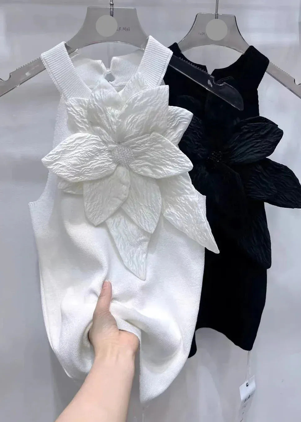 White and black sleeveless dresses with floral designs on hangers.