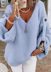 Woman wearing a light blue knitted sweater with a blurred indoor background