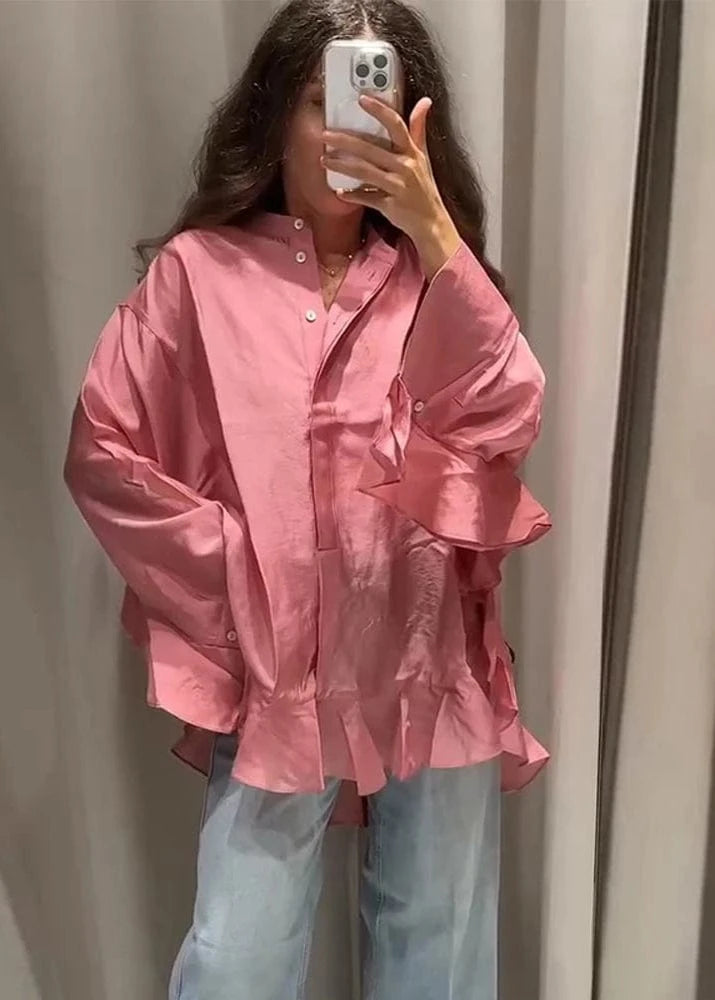 Person wearing a pink shirt and light blue jeans taking a mirror selfie.