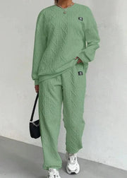 Person wearing a green cable knit outfit with a plain background