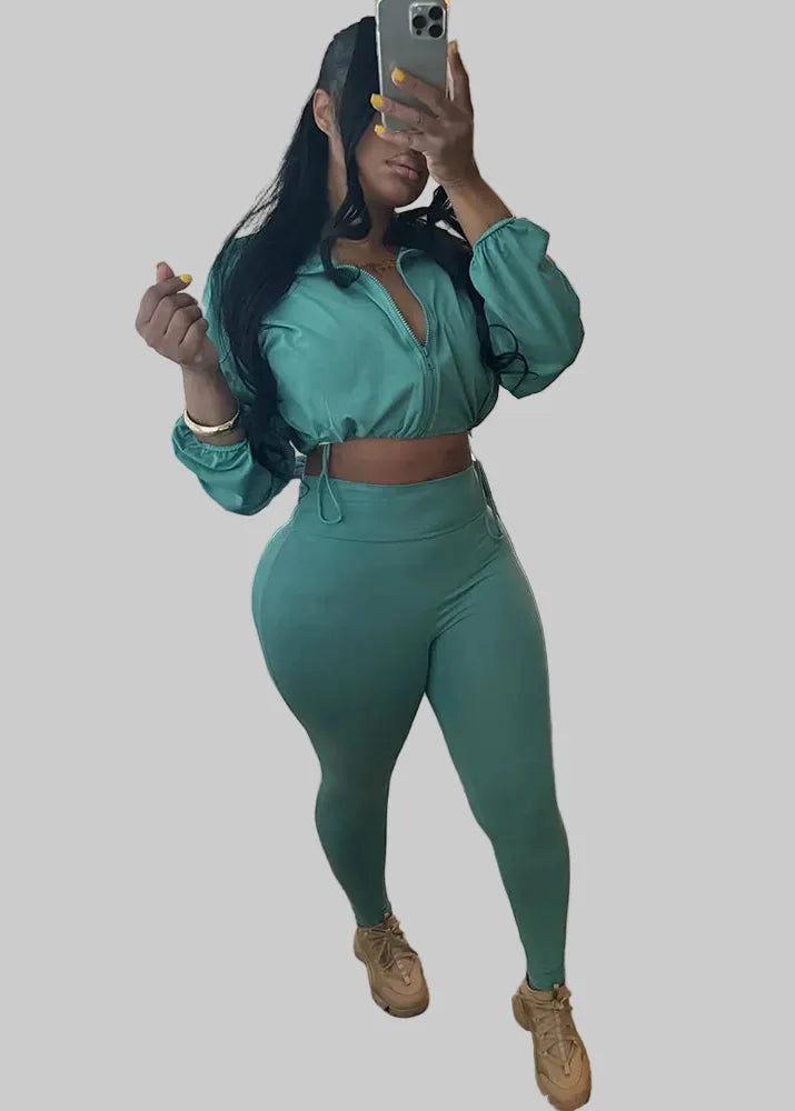 Person taking a mirror selfie wearing a green outfit in a living room.