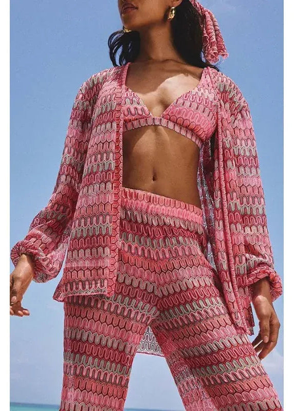 Woman wearing a pink crochet outfit against a blue sky.