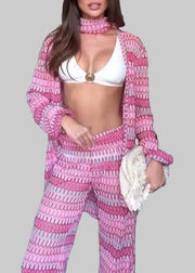 Person wearing a pink and purple crochet outfit in a room.