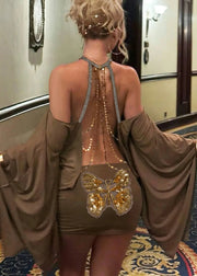 Woman wearing a brown dress with a butterfly design and gold accents in an indoor setting.