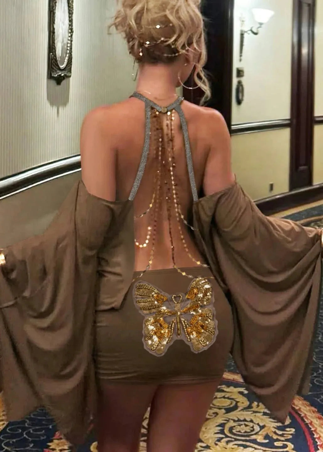 Woman wearing a brown dress with a butterfly design and gold accents in an indoor setting.