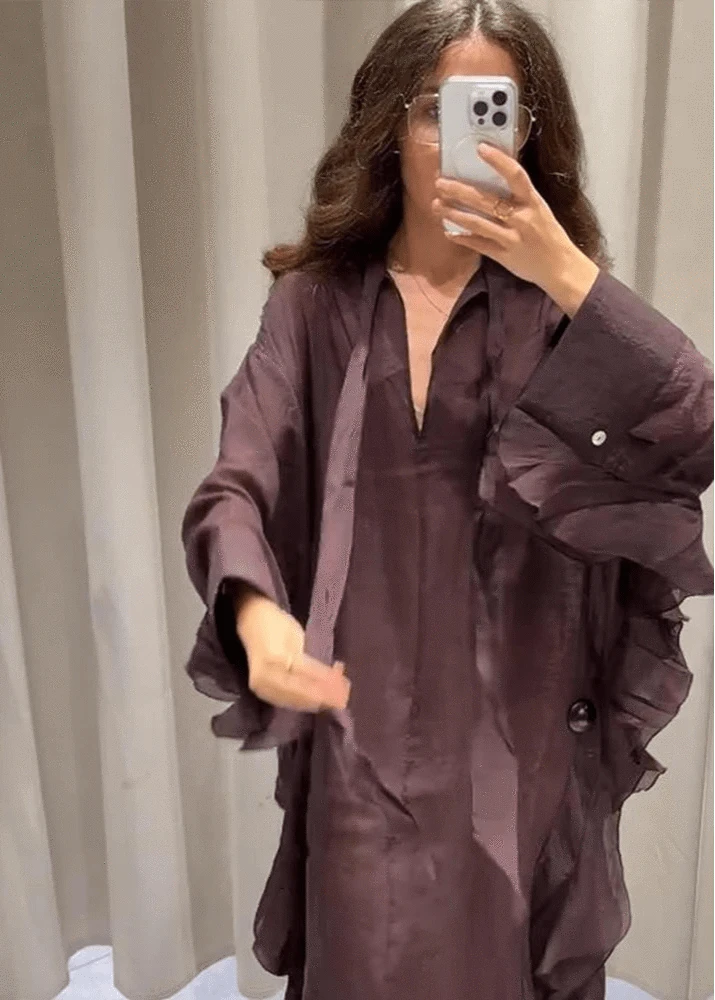 Person wearing a long, dark purple garment in a neutral setting