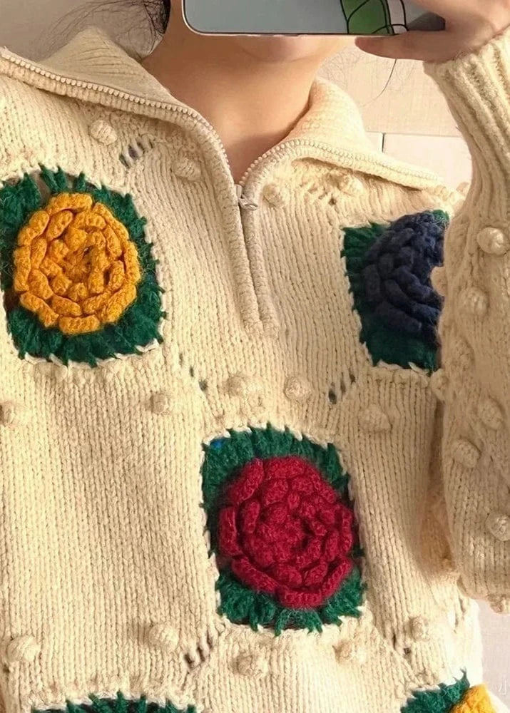 Close-up of a cream-colored sweater with colorful floral patterns.