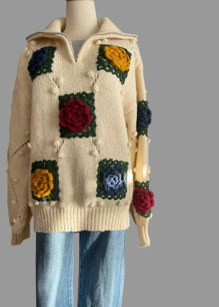 Mannequin wearing a cream-colored sweater with colorful floral patterns in a room.