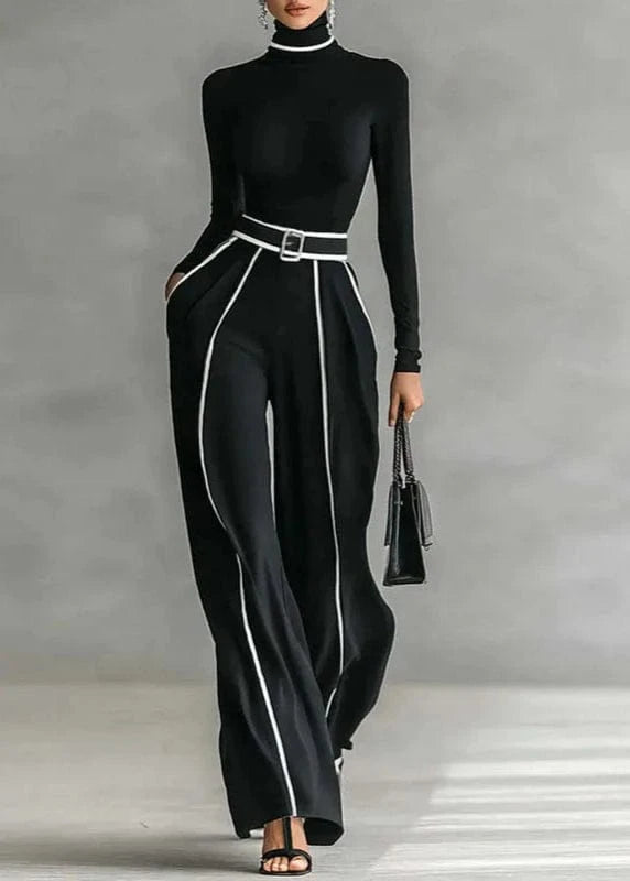 Person wearing a black outfit with white trim against a gray background