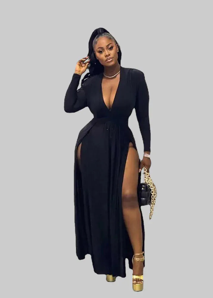 Woman in a black dress with a high slit standing in front of floral decorations and 'XSCAPE' branding.