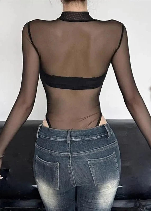 Person wearing a sheer top and jeans with a blurred background