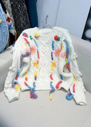 White knitted sweater with colorful tassels on a chair