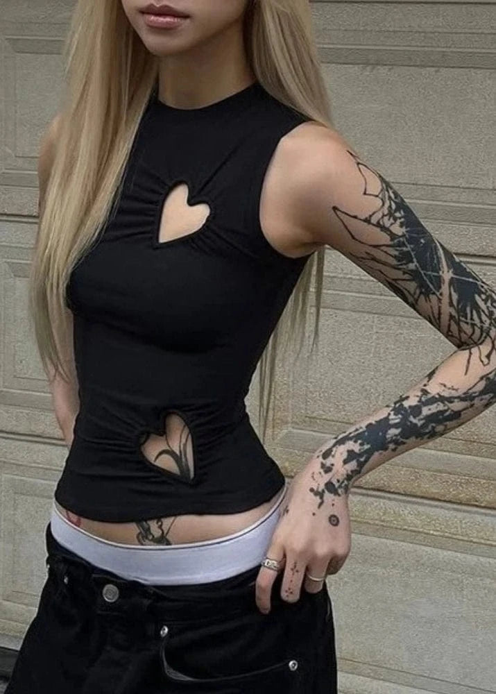 Person wearing a black sleeveless top with cut-out design and tattoos on arms.