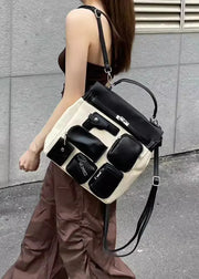 Person holding a unique handbag with black and beige design against a gray wall.