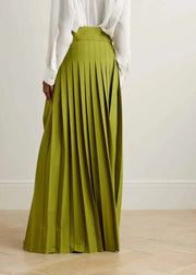 Person wearing a white blouse and green pleated skirt on a plain background