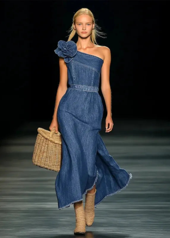 Model wearing a blue denim dress with a flower detail on a runway.