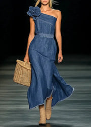 Model wearing a blue denim dress with a flower detail on a runway.