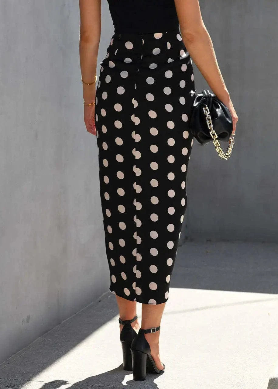 Person wearing a black polka dot skirt with a plain background