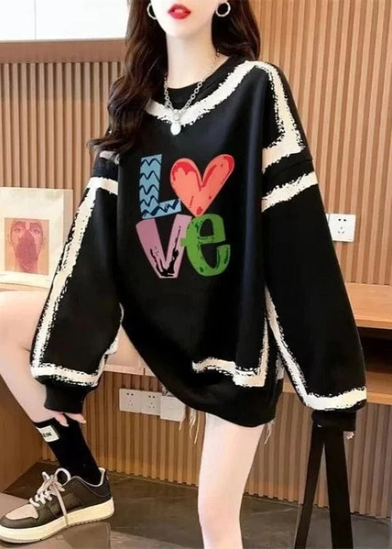 Person wearing a black sweater with colorful 'LOVE' text in an indoor setting
