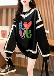 Person wearing a black sweater with colorful 'LOVE' text in an indoor setting