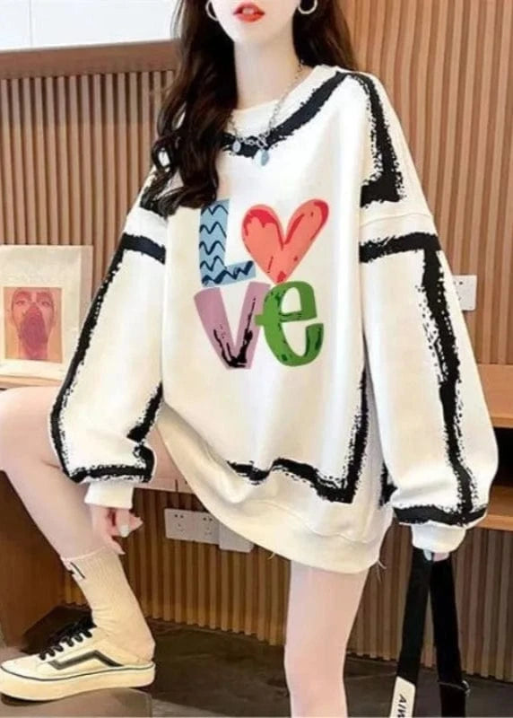 Person wearing a white sweater with colorful 'LOVE' design sitting in an indoor setting.