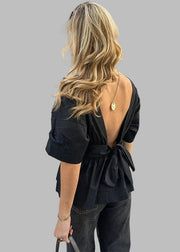 Woman in a black open-back top walking on a city street