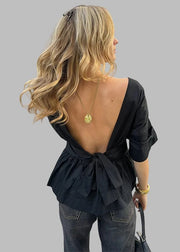 Woman wearing a black open-back top and jeans on a city street.