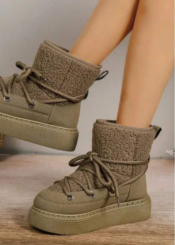 Brown fleece-lined boots on a wooden floor with a plant in the background