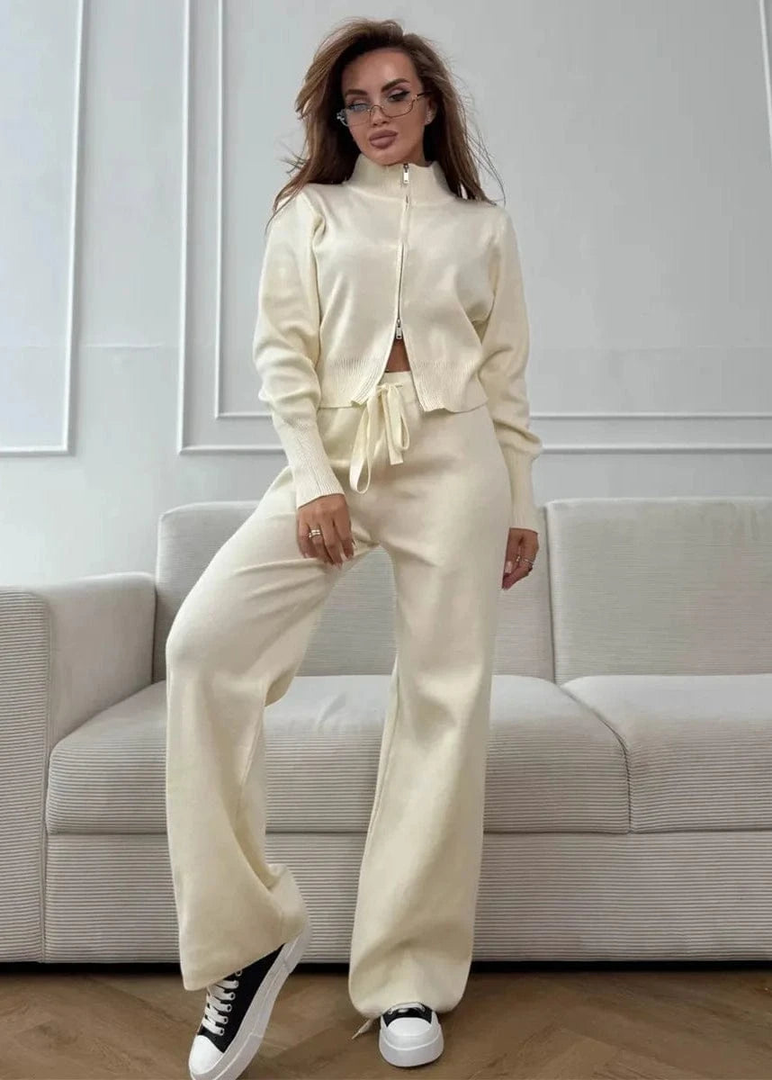 Woman in a cream-colored outfit standing in a modern living room.