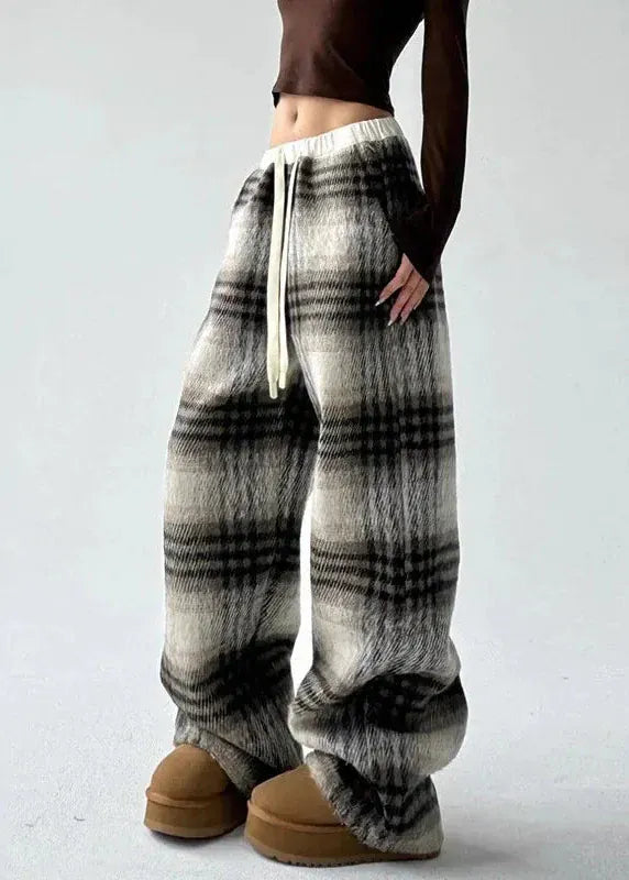 Plaid patterned pants worn by a person on a plain background